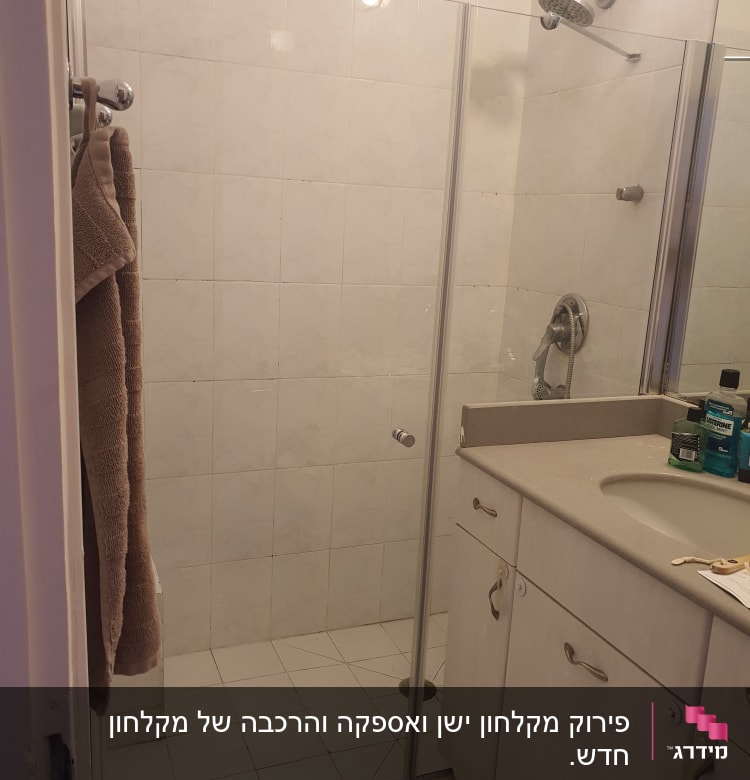 מקלחת עם דלת זכוכית ומגבות תלויות